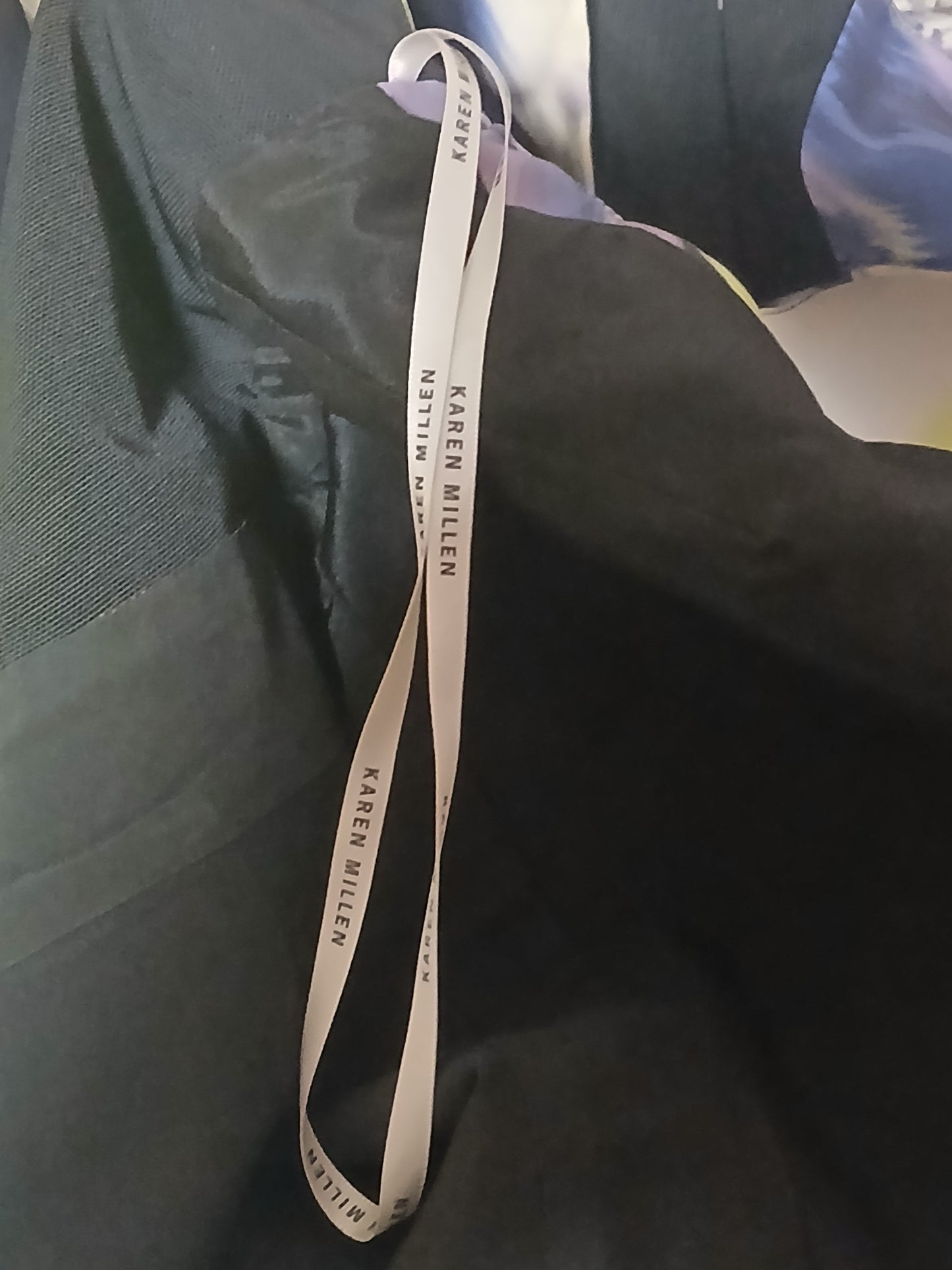 Department Store UK Karen Millen dress featuring a branded white hanging ribbon against a black fabric background